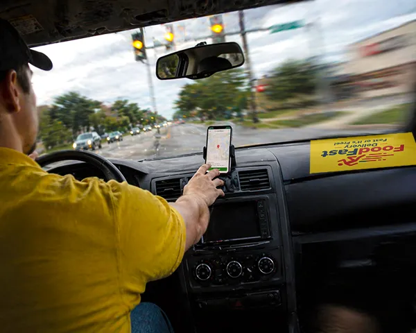 Oklahoma delivery driver looking at his company's phone app while approaching an intersection, illustrating distracted driving in a commercial vehicle accident scenario